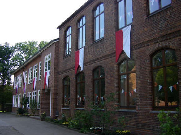 Die Rote Schule hat ihren Namen durch die Farbe der roten Backsteine. Man sieht sie auf dem Foto mit rot - weißen Fahnen zur Einschulungsfeier geschmückt